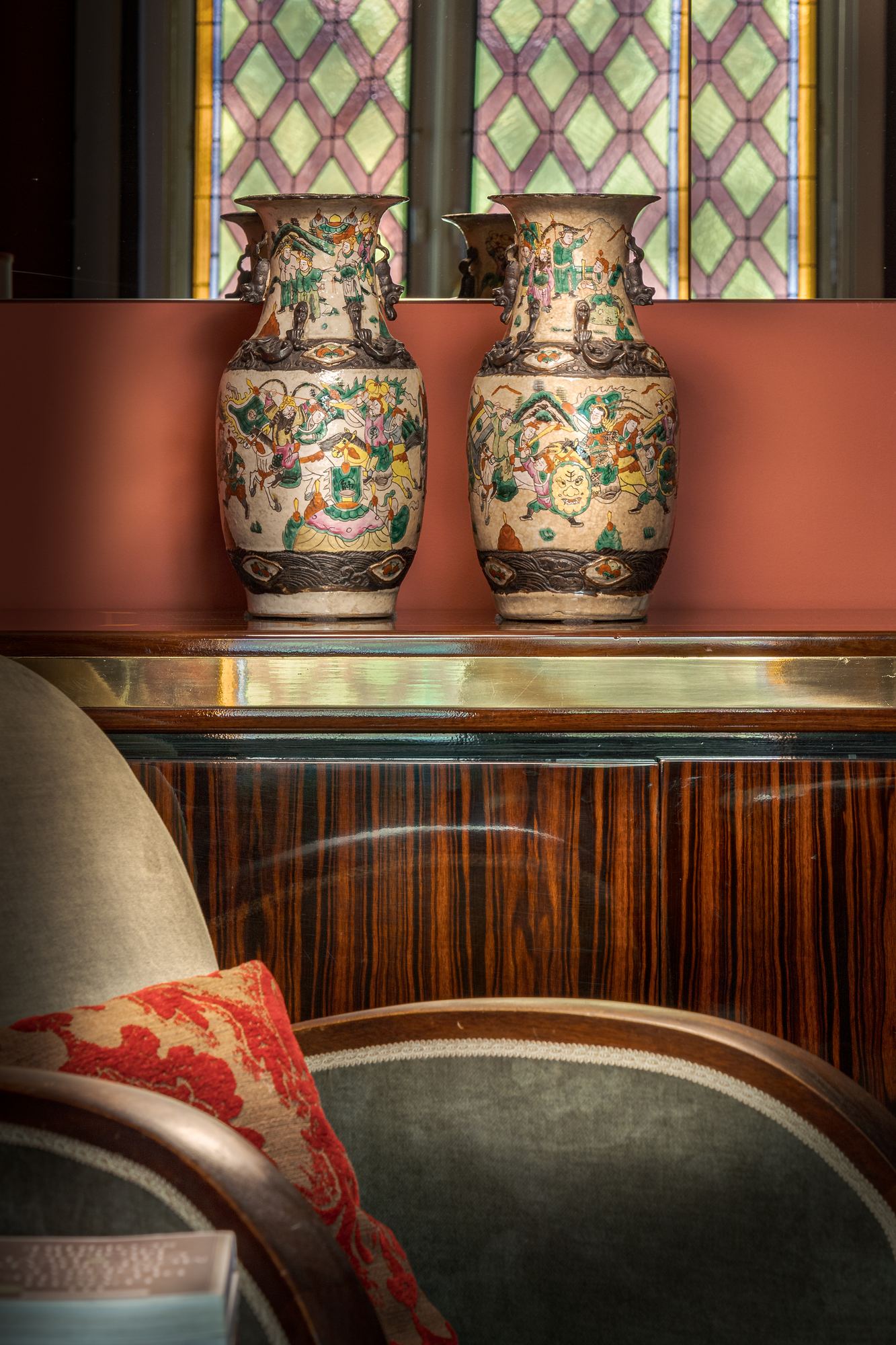 Pair of painted porcelain vases on a dark wood cabinet