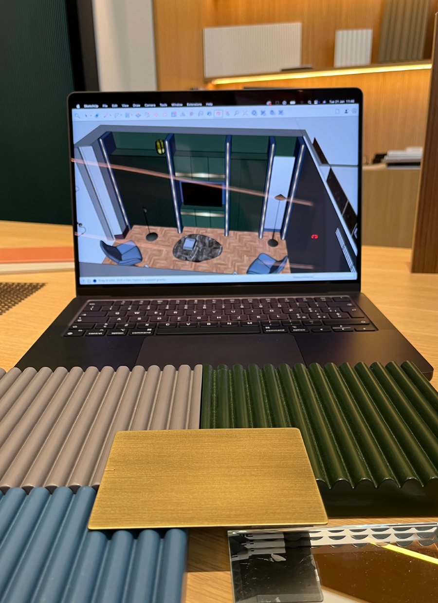 Laptop with a 3D model beside fluted panels and a brass sample