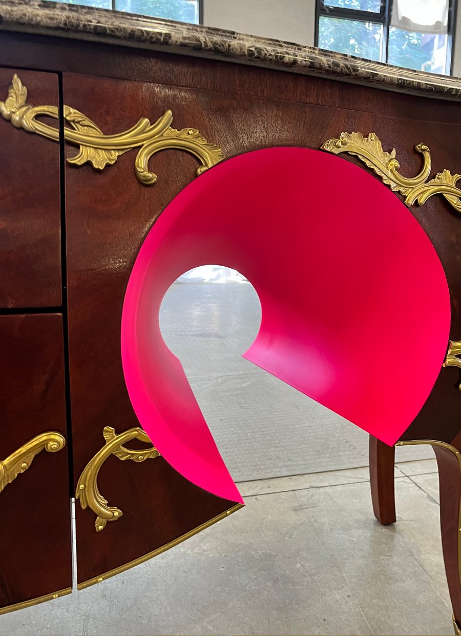 Antique commode cut open with a pink lacquered curl