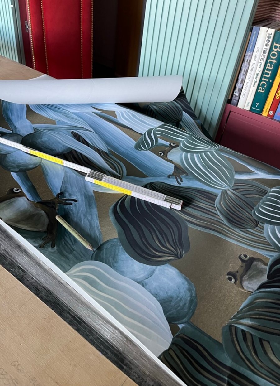 Leaf wallpaper being fitted beside bookshelves and green fluting